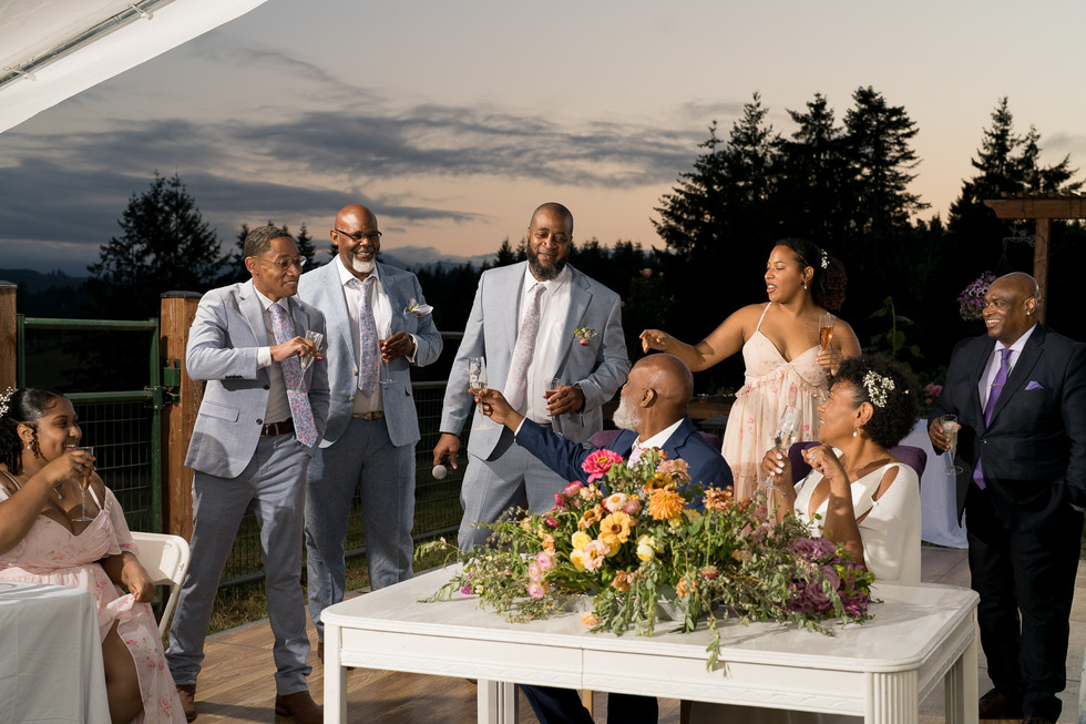 Joyful guests toast at an intimate farm wedding with floral centerpiece.