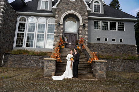 Bride, groom on stone steps of large house, fall wedding White Salmon.