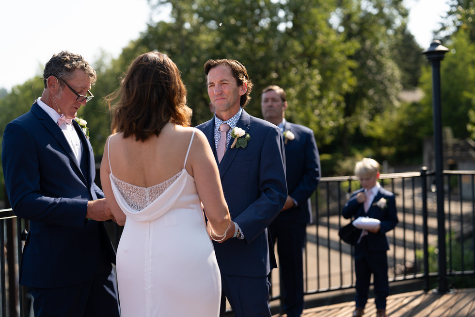 Groom looking at bride during elegant outdoor summer wedding ceremony.