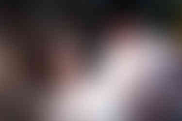 Smiling bride looks affectionately at groom in cowboy hat during wedding.