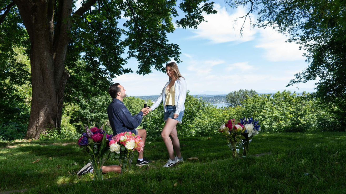 Man proposing to woman outdoors with flowers