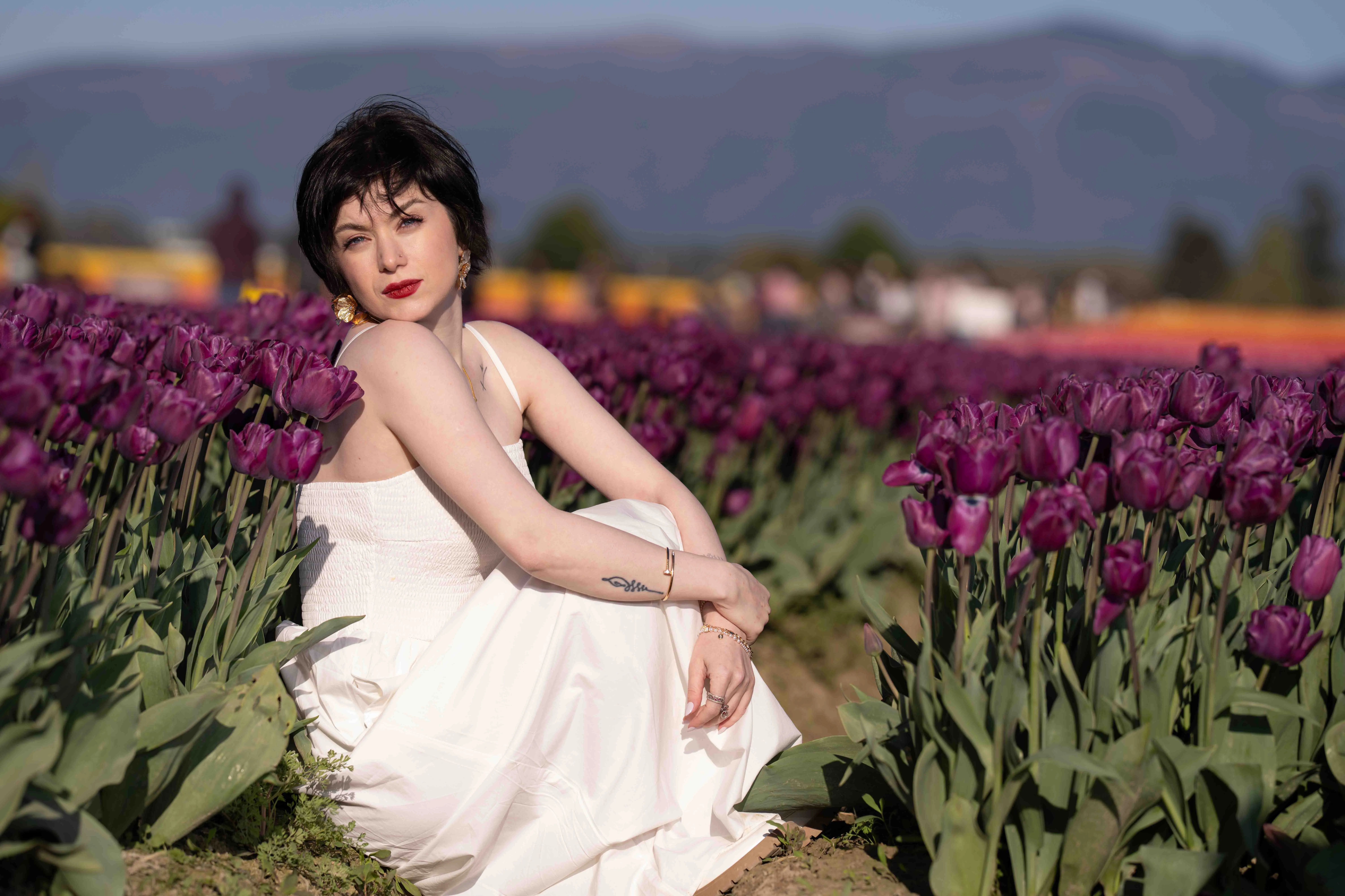 Woman in white dress sitting in purple tulips, Skagit Tulip Festival.