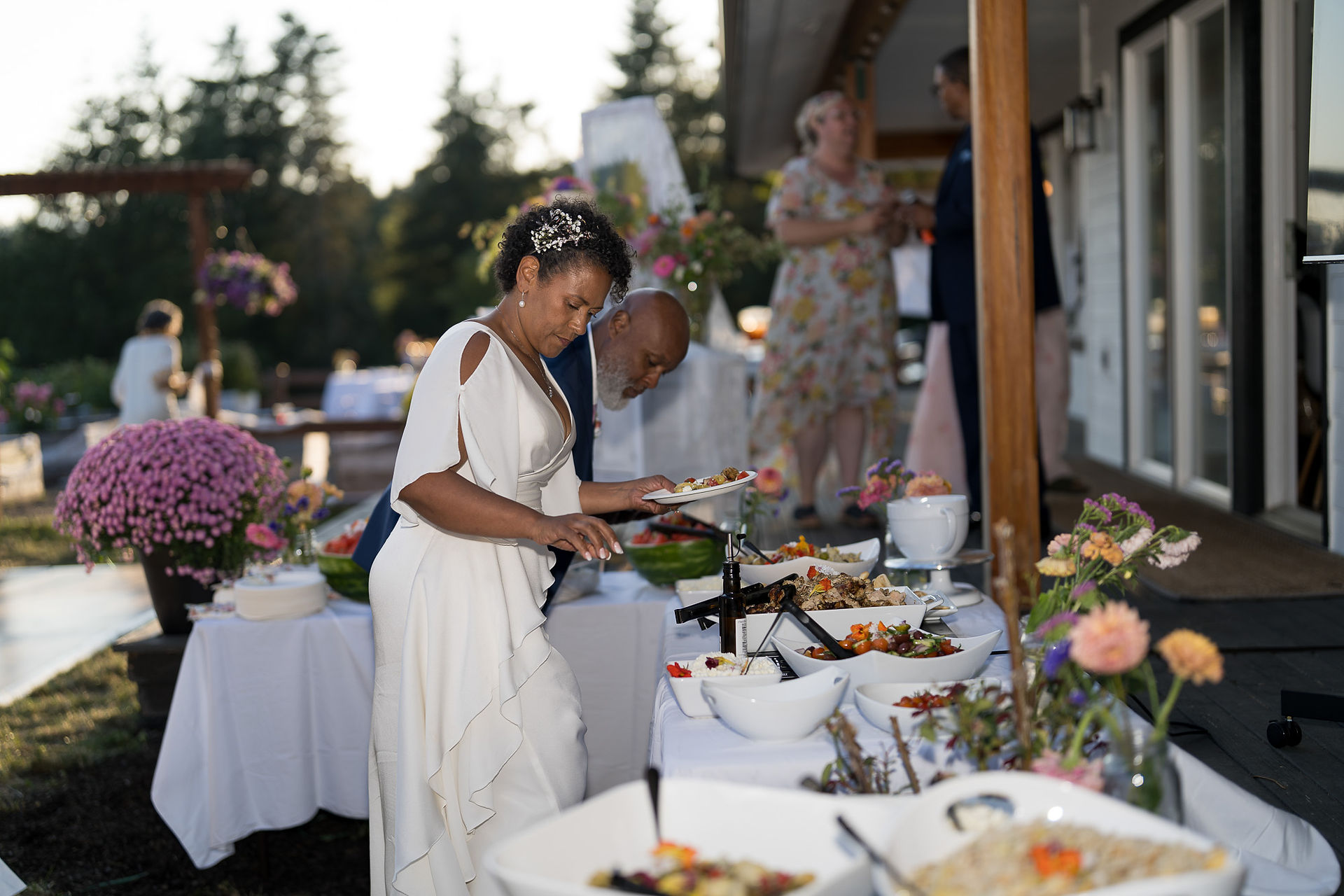Bride and groom serving food at an intimate farm wedding buffet.