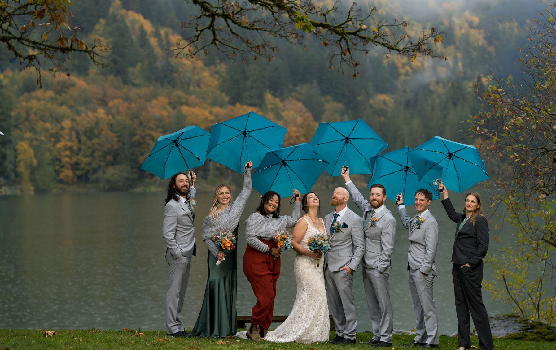 Group of happy people with blue umbrellas during wedding with lake views. PhotoYari