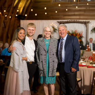 Four smiling people posing at an elegant indoor wedding reception.
