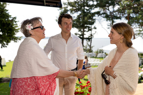 Two women shaking hands, man smiling at backyard wedding on Camano Island.