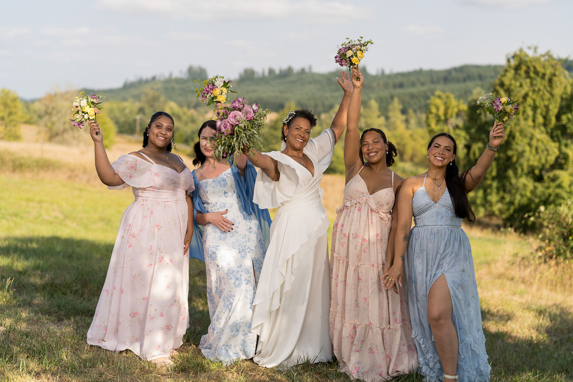 Six women celebrating with bouquets outdoors at an intimate farm wedding.