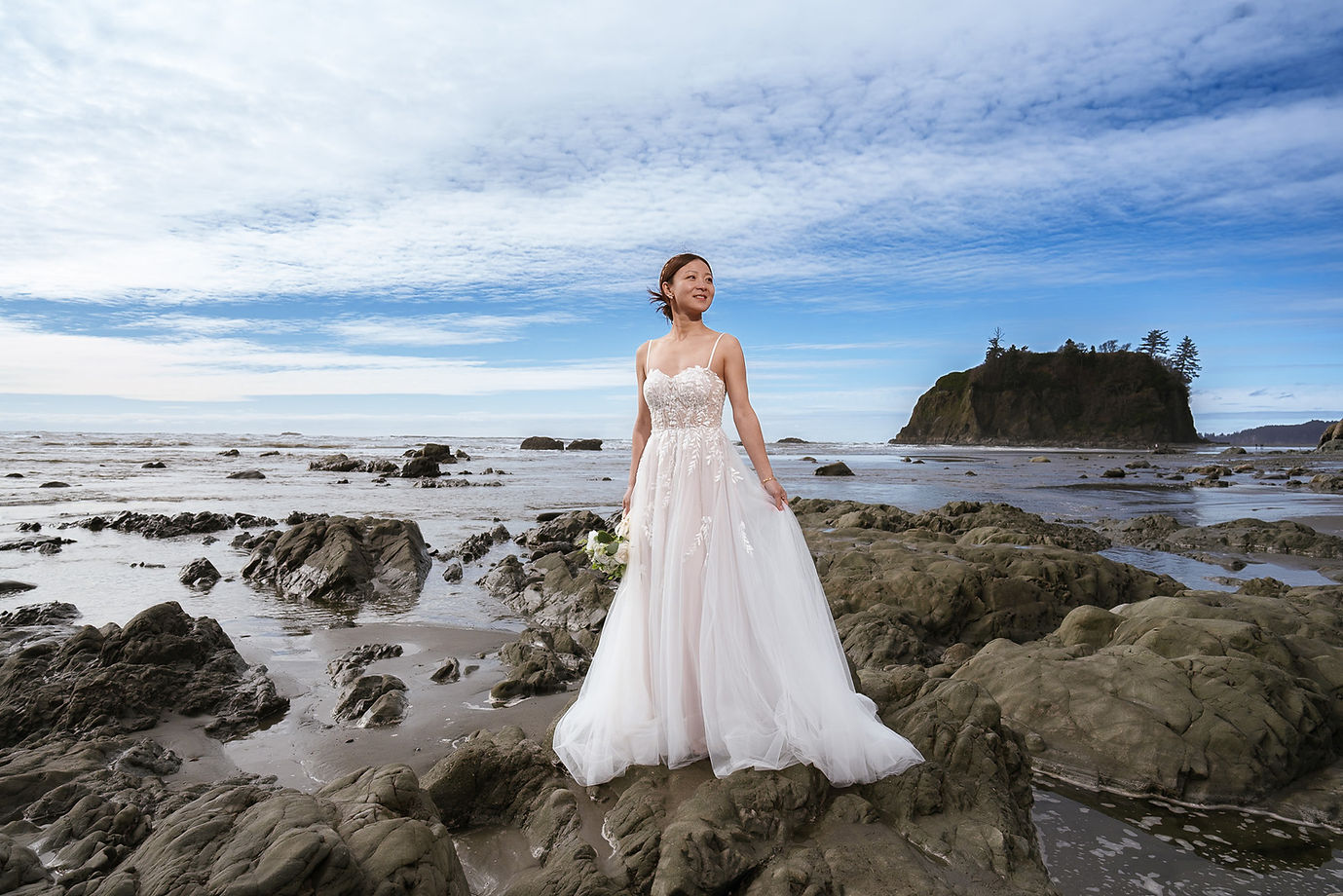 Bride in wedding dress on a rocky coast