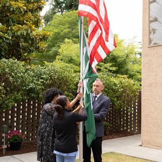 Flag raising ceremony: three people raising US and another flag