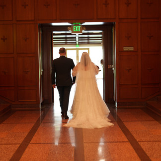Bride and groom walk towards EXIT sign leaving ceremony.