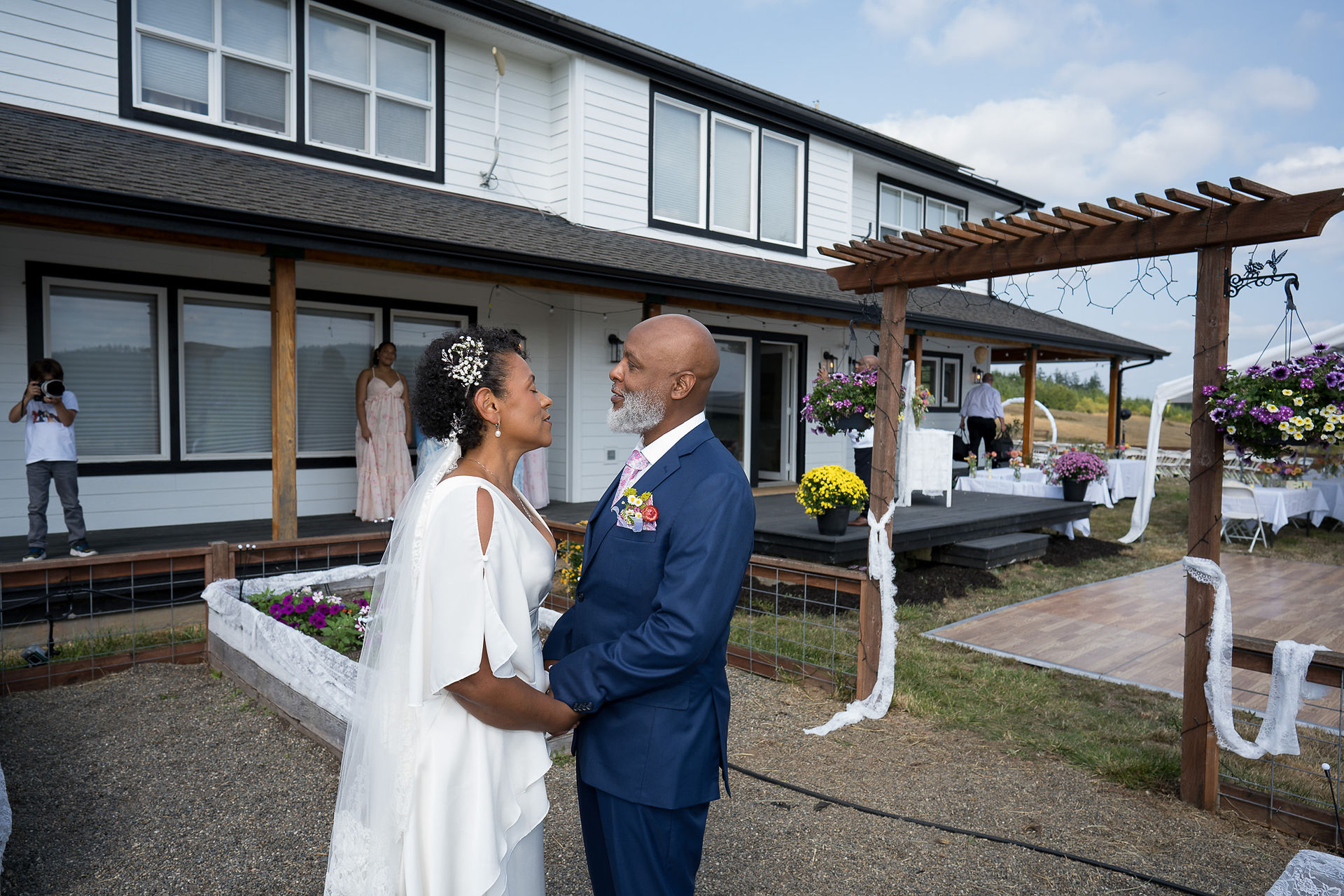 Happy couple holding hands, gazing lovingly at their farm wedding.