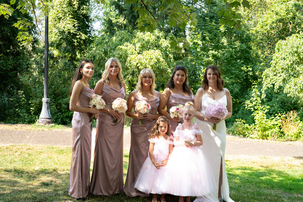 Bride, bridesmaids, flower girls smiling with bouquets at Oregon wedding.