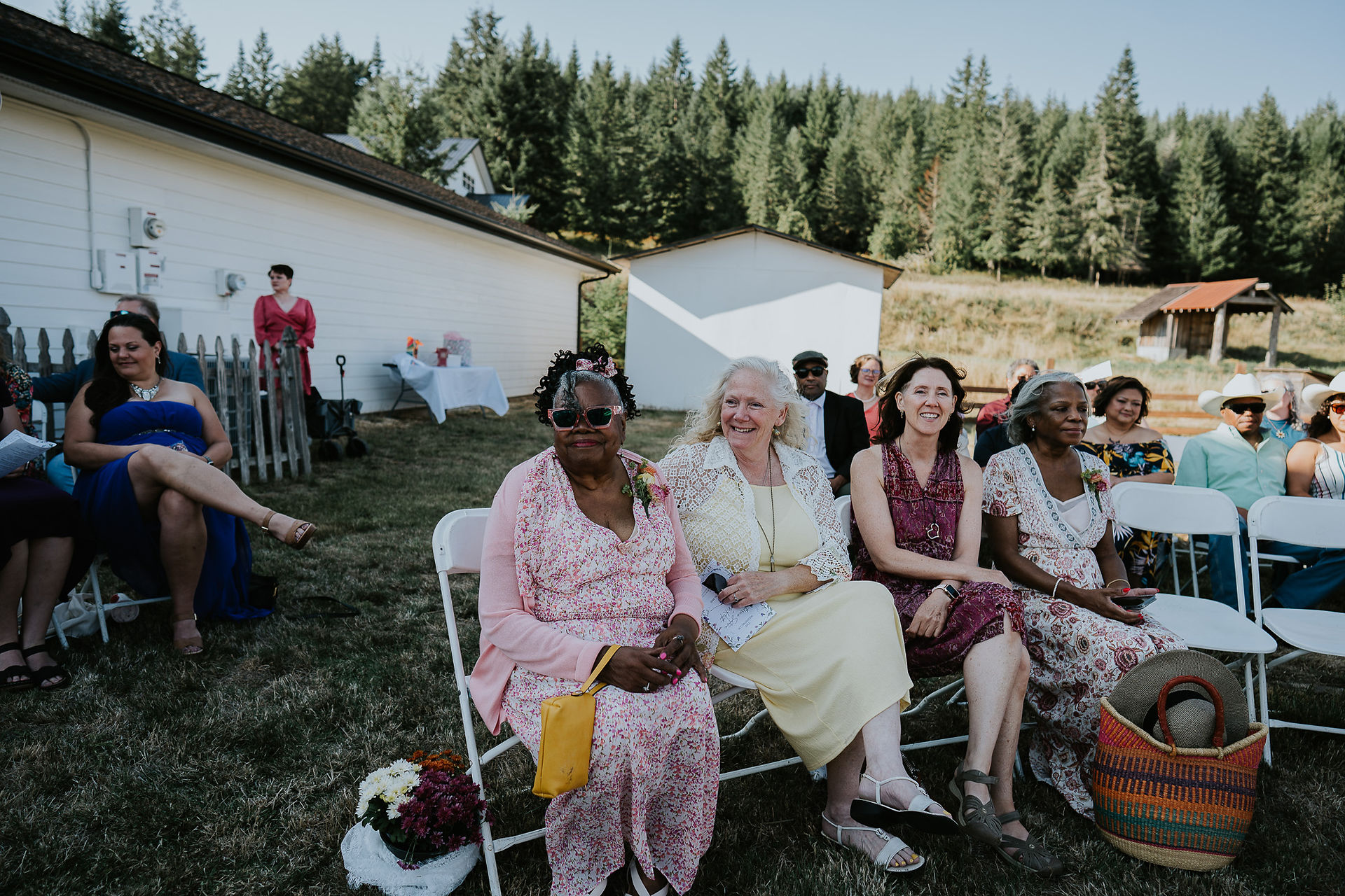 Smiling guests seated on chairs enjoying an intimate farm wedding.