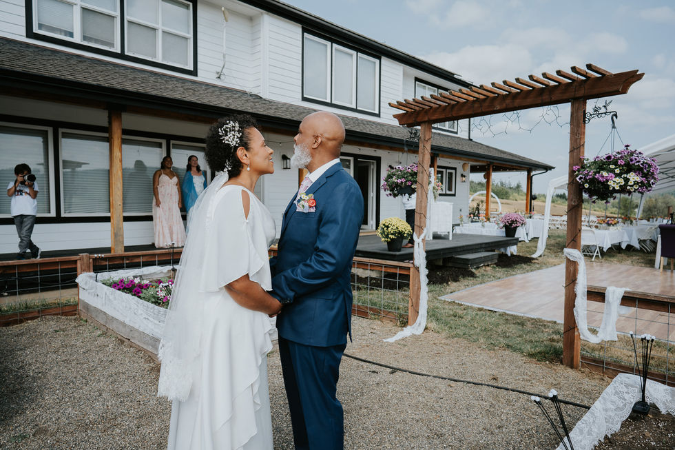 Bride and groom holding hands, exchanging vows at intimate farm wedding.