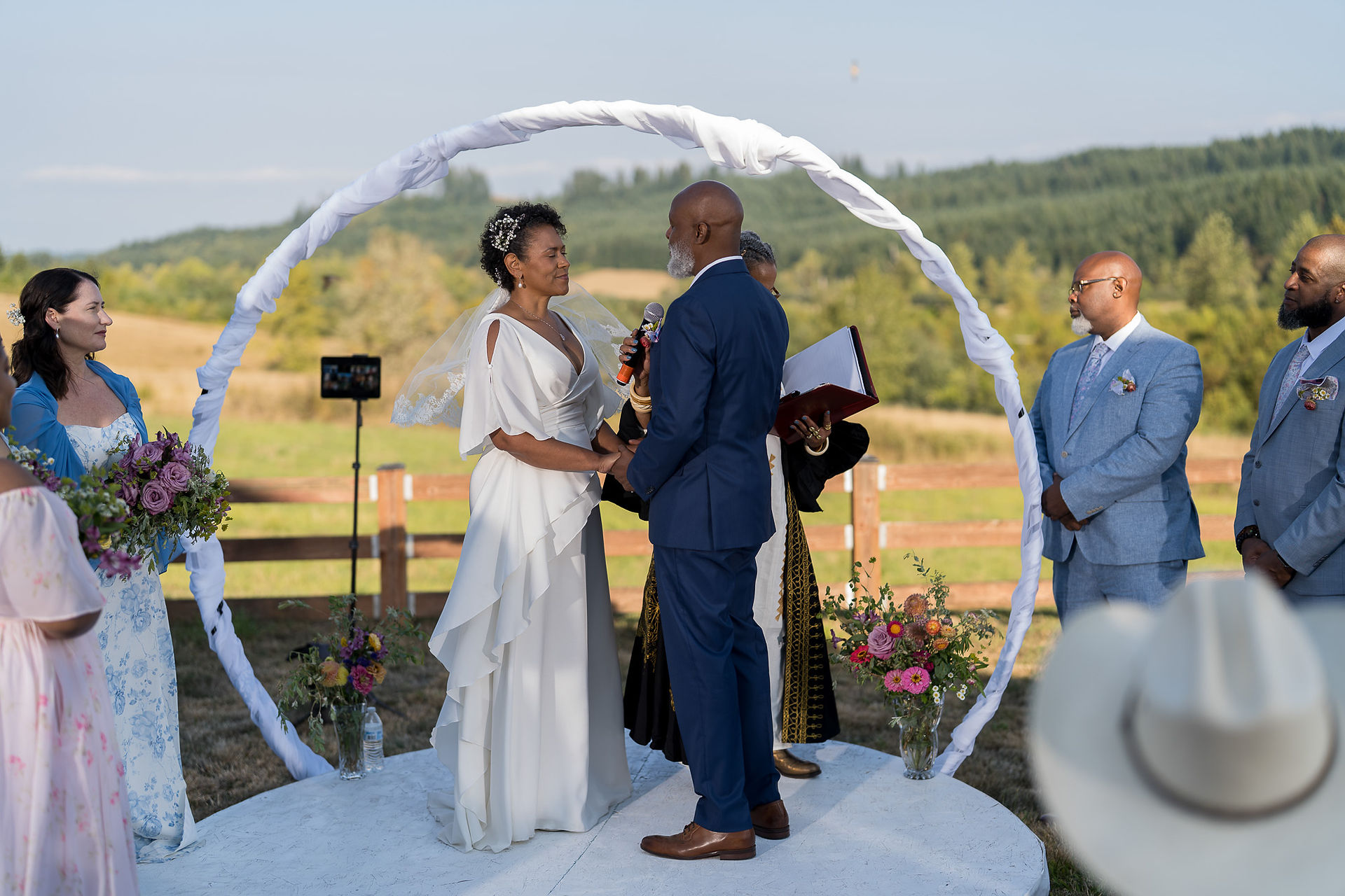 Couple exchanging vows, holding hands during outdoor wedding ceremony.