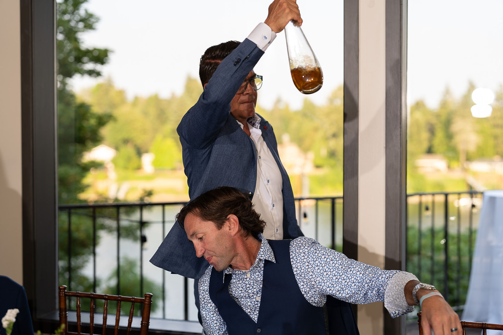 Guest playfully pouring drink from bottle over another guest's head.