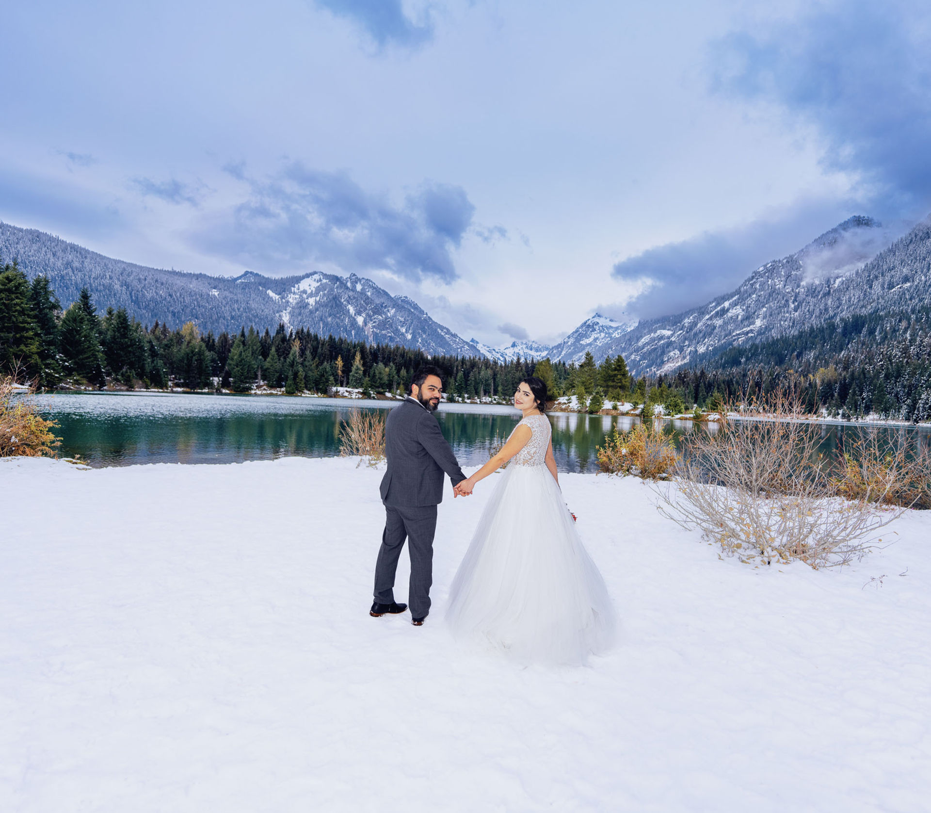 Bride and groom during a winter elopement beside a snowy alpine lake in the Pacific Northwest