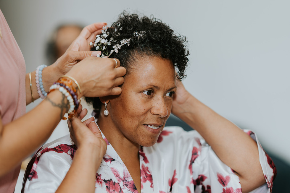 Bride having small white flowers placed in her curly hair.