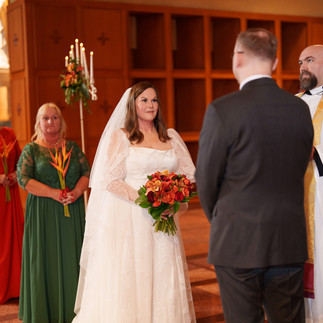 Bride in white gown looks at groom during wedding ceremony.
