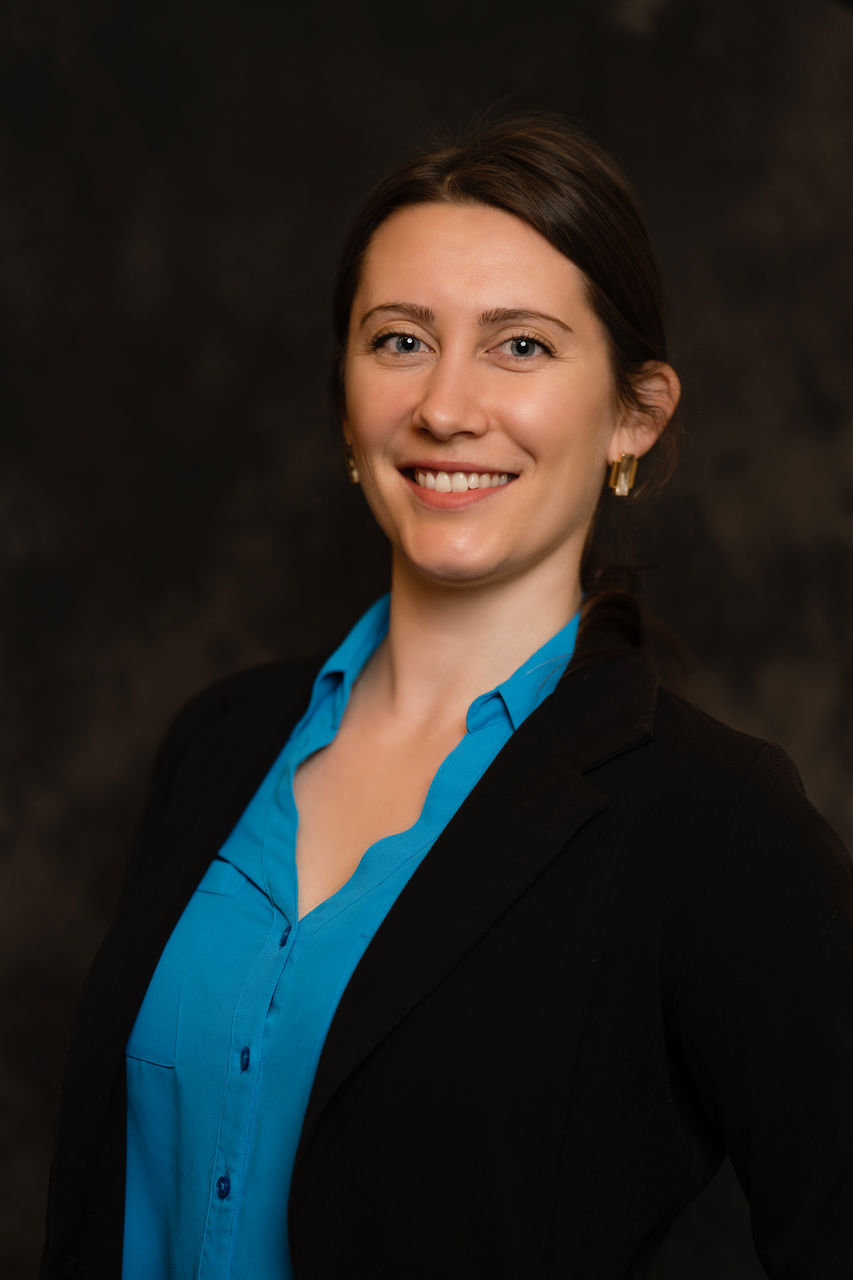 Headshot: Smiling woman in a blue shirt and black blazer