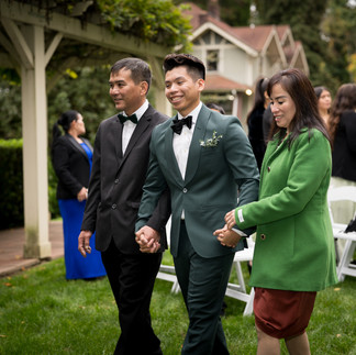 Groom escorted by parents down the aisle at an outdoor wedding.