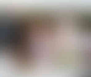 Woman serves watermelon from outdoor buffet as man laughs beside her.