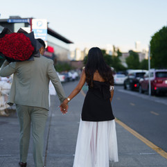Couple holding hands, man carrying red roses