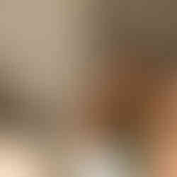 Young woman smiling brightly at a table with a blue drink.