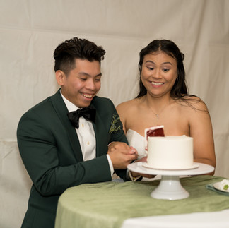 Smiling couple cuts white wedding cake together, a celebration moment.