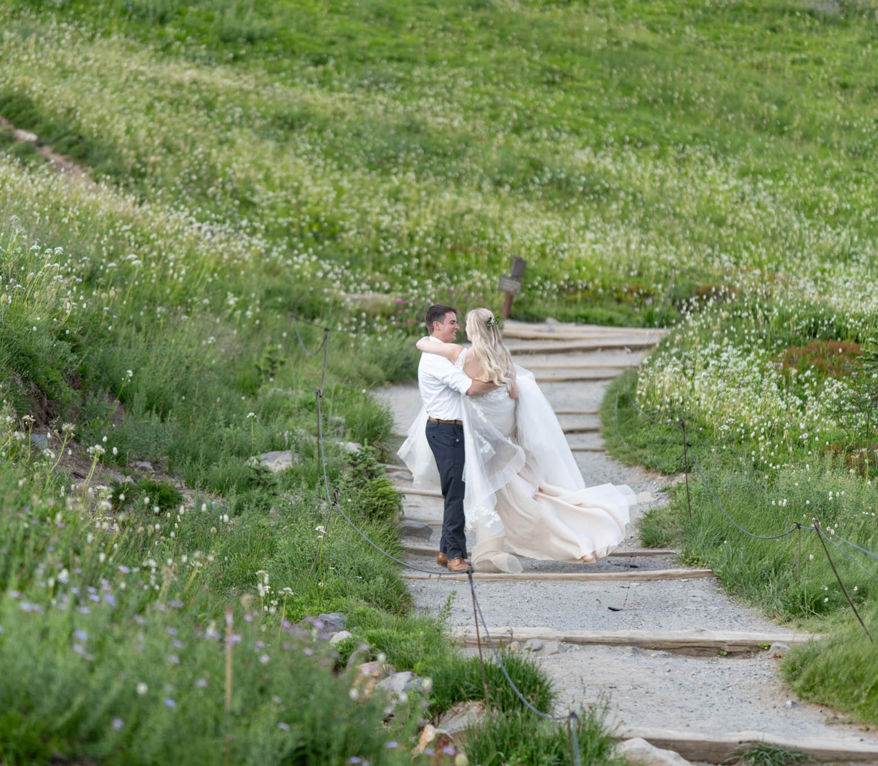 Bride and groom posing on mountain steps surrounded by green alpine scenery in the Pacific Northwest