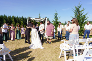 Bride and groom embrace at outdoor wedding ceremony with guests, Reserved sign.