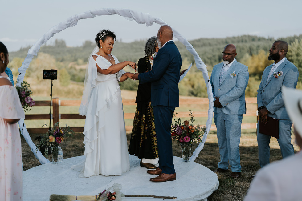 Bride and groom exchanging rings during their outdoor wedding ceremony.
