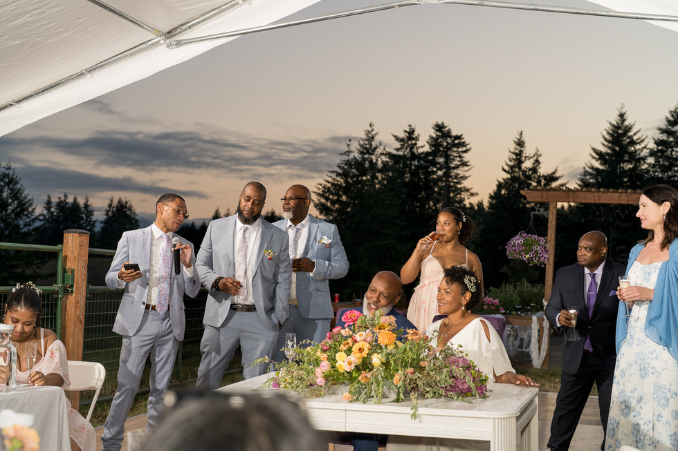 Guests listening intently to a man giving a speech outdoors.