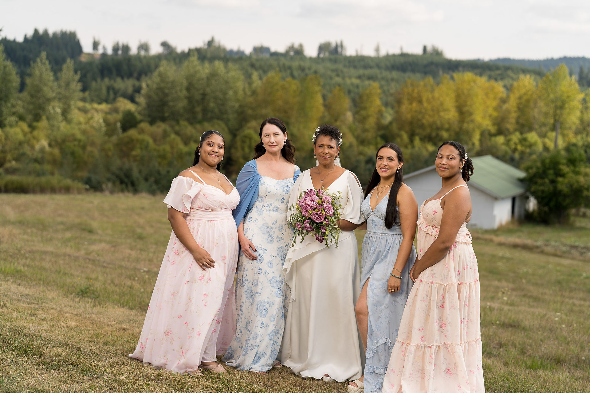Smiling bride and four bridesmaids outdoors at a rustic farm wedding.