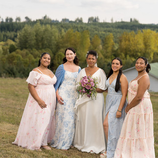 Smiling bride and four bridesmaids outdoors at a rustic farm wedding.