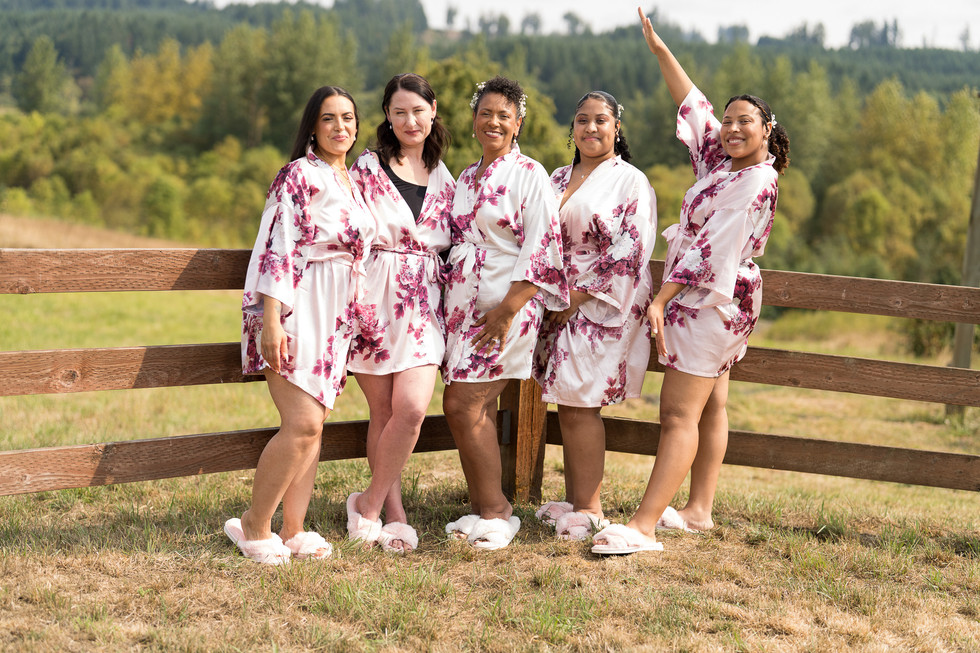 Five women in floral robes posing at an intimate farm wedding.