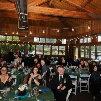 Wedding guests applauding in rustic reception hall at Gold Mountain Golf Club