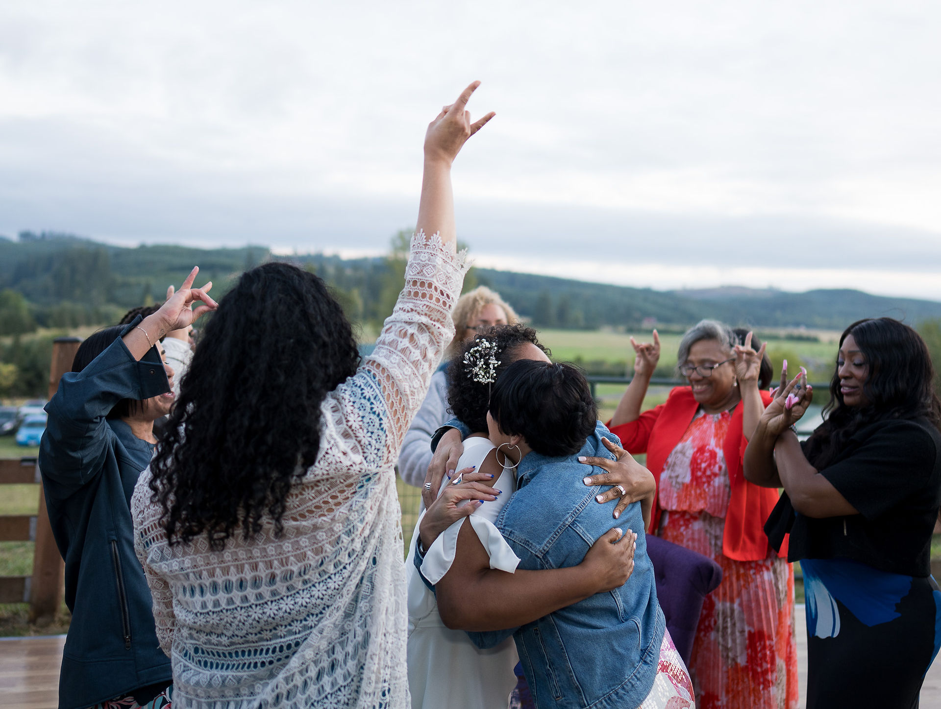 Women hugging and cheering happily at an outdoor country gathering.