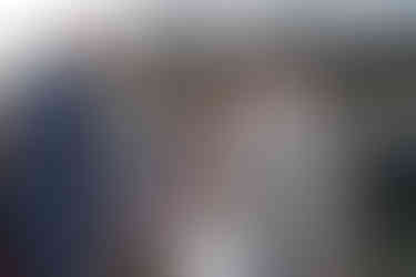 Bride walks down aisle with man, holding purple bouquet, outdoor wedding.