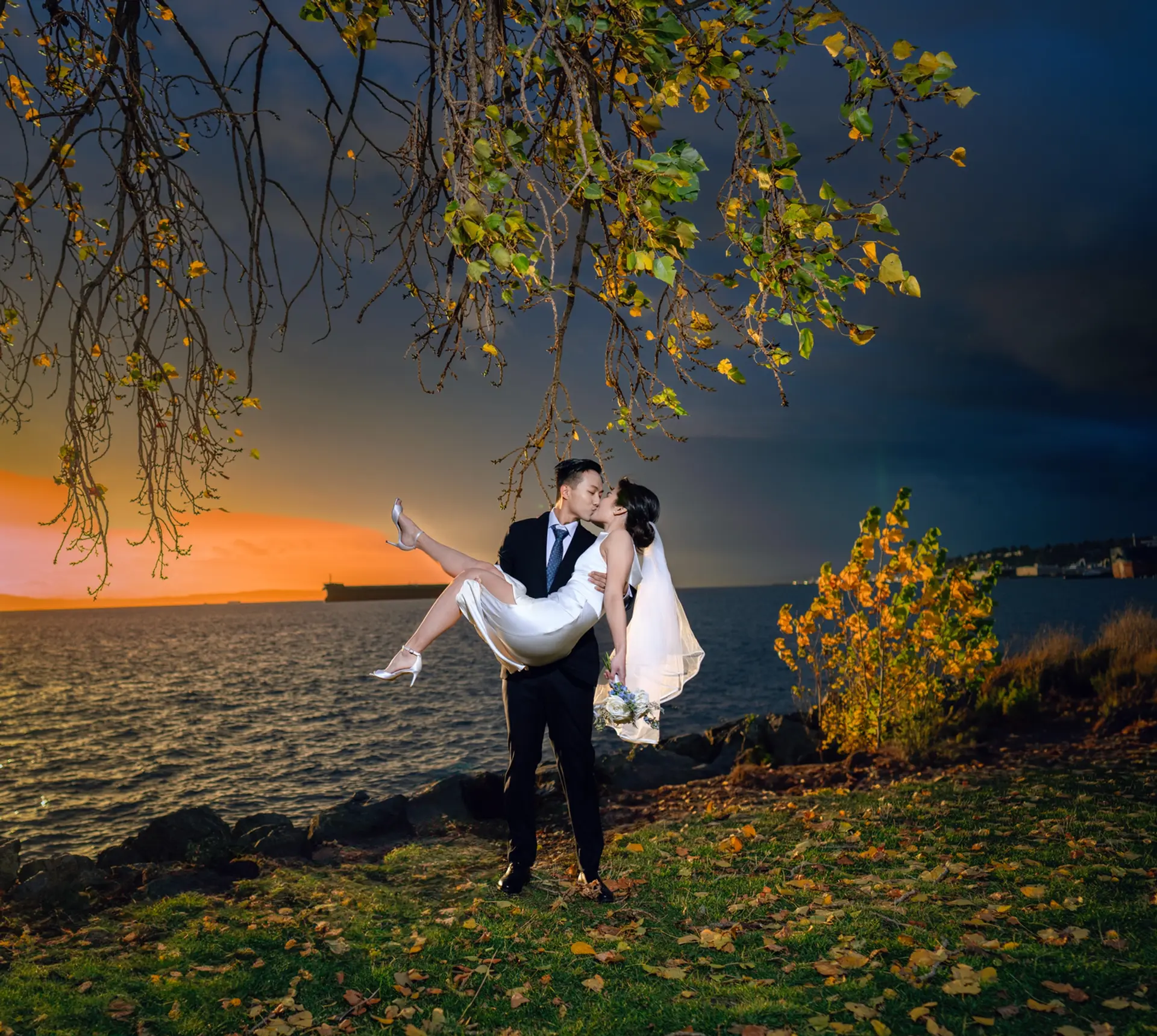 Romantic sunset wedding photo: Groom carrying bride, kissing