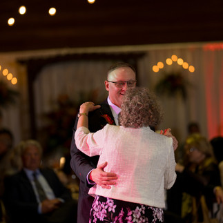 Joyful couple slow dancing at a beautiful, warmly lit wedding reception.