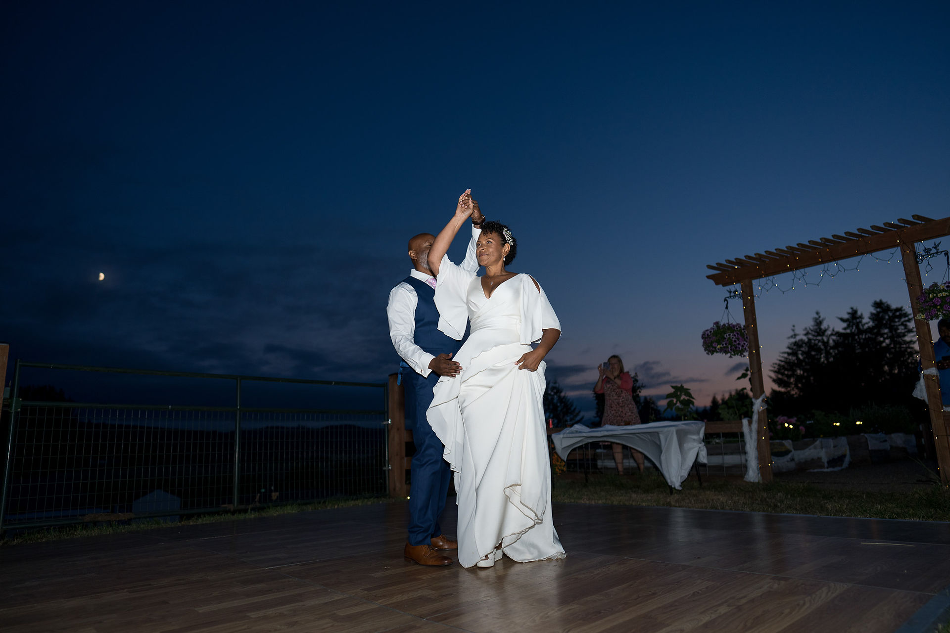 Bride and groom dancing outdoors on wooden floor at intimate farm wedding.