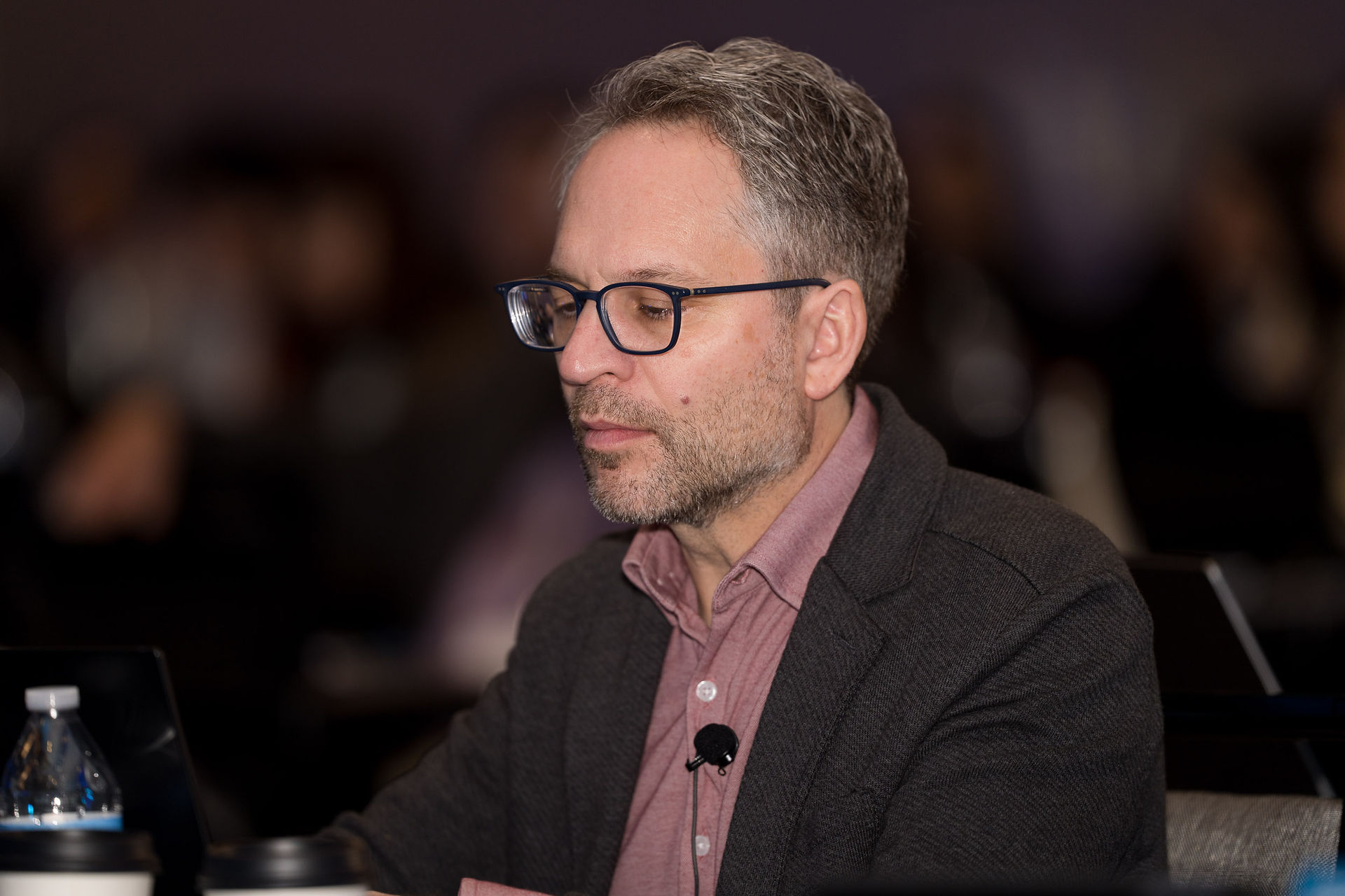 Man with glasses and microphone at symposium