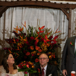 Guests attending reception with vibrant red and orange floral centerpiece.