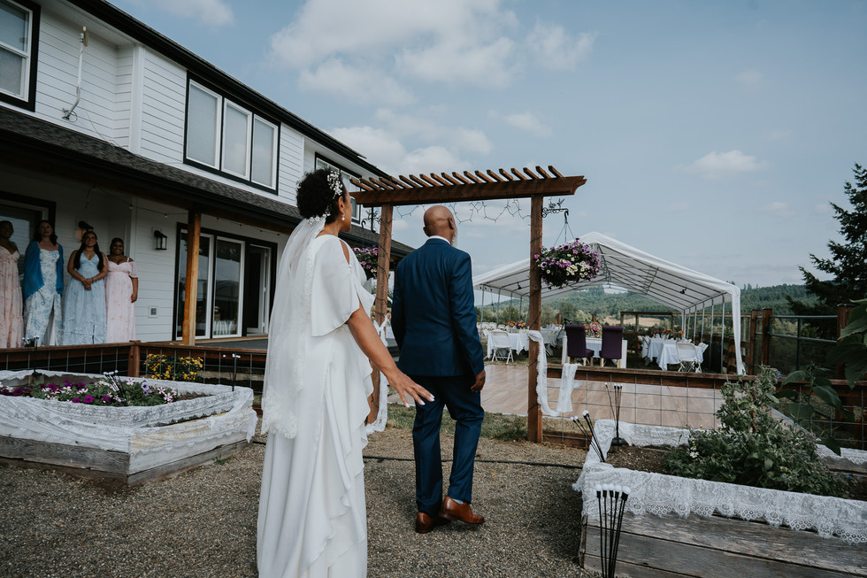 Bride and father walk towards decorated farm wedding ceremony arbor.
