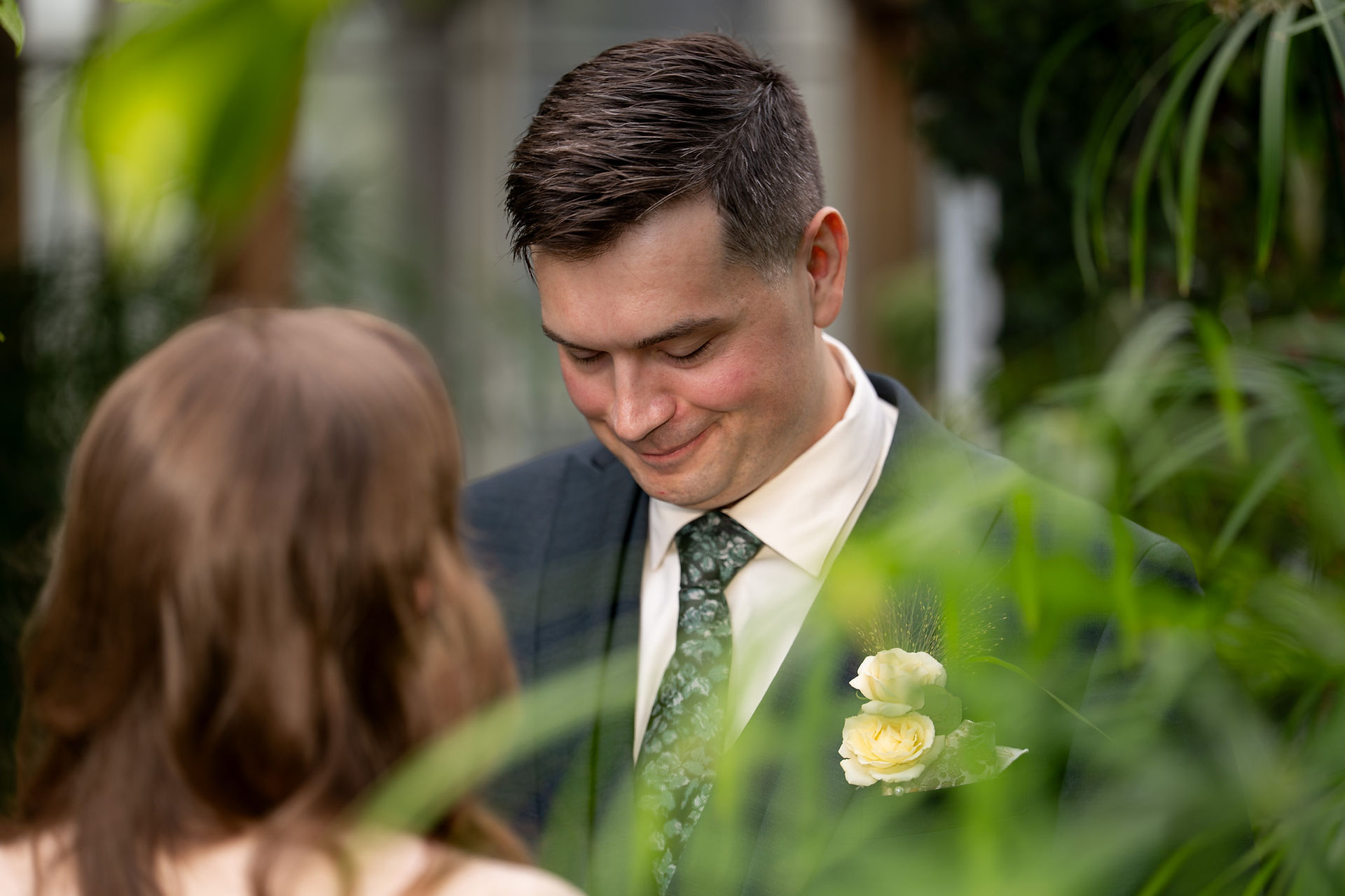 Groom smiling at bride inside Volunteer Park Conservatory in Seattle