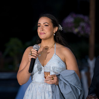 Smiling woman holds microphone, glass, speaks at evening event.
