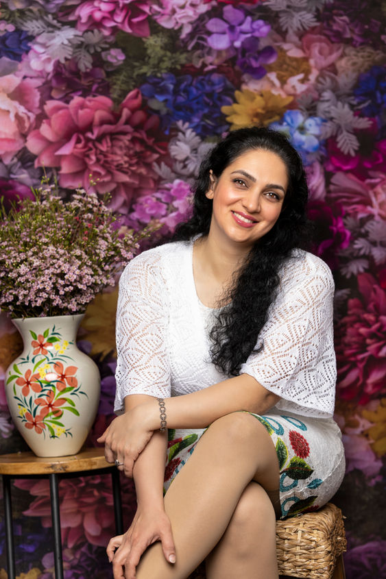 Smiling woman in white dress, floral backdrop