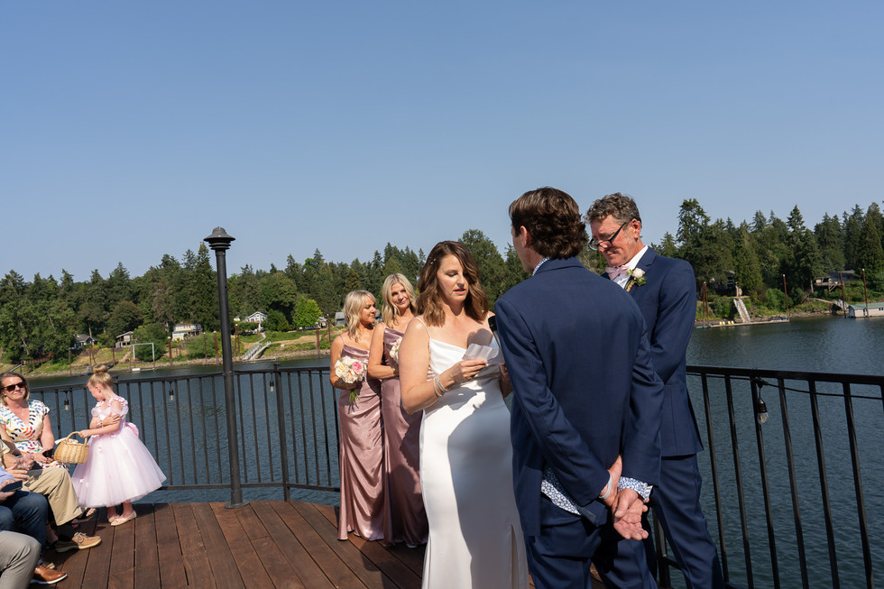 Bride and groom exchanging vows at beautiful outdoor lakeside wedding ceremony.