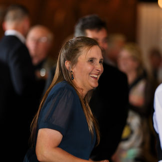 Joyful woman in dark blue dress laughing at a reception.
